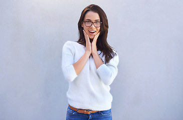 Image showing Happy woman, portrait and surprise with glasses in fashion for good news on a gray studio background. Face of female person, brunette or model with shock for winning, promo or bonus on mockup space