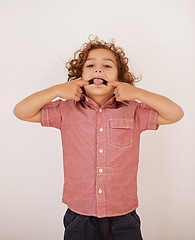 Image showing Boy, kid and portrait in studio with tongue out for funny face, joke or games by white background. Child, mouth and comic gesture with fashion, playful and emoji with trendy style, shirt or clothes