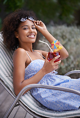 Image showing African, woman and sunbathing with cocktail for summer on vacation, tropical drink and sunglasses for time fun. Happy, smile or female person laying on resort deck, comfortable or wellness or liquid