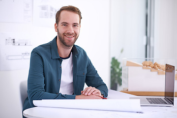 Image showing Portrait, smile and blueprint with architect man in office with documents for building, design or planning. Architecture, construction and laptop with confident young developer in creative workplace