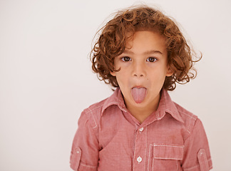 Image showing Boy, child and portrait in studio with tongue out for funny face, joke or games by white background. Kid, mouth and comic gesture with fashion, playful and emoji with trendy style, shirt or clothes