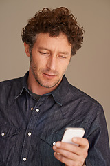 Image showing Mature man, phone and texting in studio for thinking, reading or scroll for search on web by background. Person, smartphone and check for email, notification or post on social network with mobile app