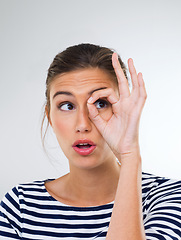 Image showing Woman, circling eye and peeking with fun, happiness and person on white studio background. Model, mockup space or girl with hand gesture and explore with optometry and vision with discovery or search