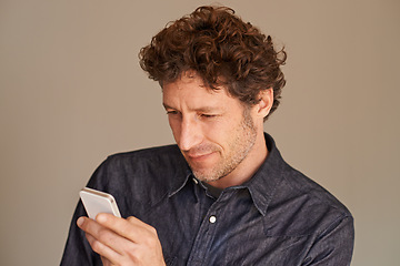 Image showing Mature man, smartphone and texting in studio for thinking, reading or scroll for search on web by background. Person, phone and check for email, notification or post on social network with mobile app