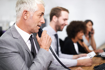 Image showing Call center, man and landline in office for customer service with telemarketing, help desk and conversation. Senior, employee and face of consultant with telephone for support, telesales and advice