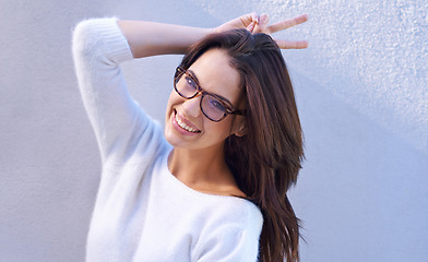 Image showing Portrait, glasses and woman with sign for sweater with warm, fashion and casual for winter. Studio background, female person with happiness, smile and girl with jersey of wool for comfort in New York