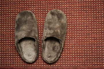 Image showing soft brown house slippers on the rug 