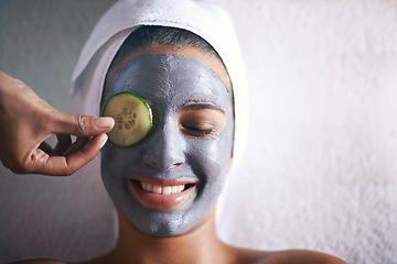 Image showing Woman, face mask and smile with hands and cucumber for facial, spa wellness and beauty treatment. Above, towel and calm female person with skincare and relax at hotel with glow and cosmetic cream
