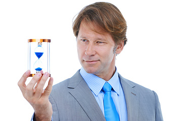 Image showing Businessman, checking and time management with hour glass for schedule or limit on a white studio background. Young man or employee looking at sand for minutes, seconds or deadline on mockup space