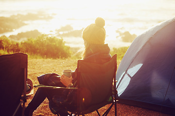 Image showing Sunset, camping and woman by tent on vacation, adventure or holiday in nature for travel. Evening, coffee and back of female person relaxing and drinking cappuccino in chair outdoor for weekend trip.