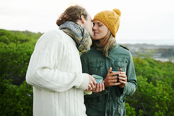 Image showing Kiss, couple and drinking coffee in nature on holiday, vacation or travel together on adventure for hiking in winter. Trekking, man and woman with tea cup outdoor in the countryside, love and romance