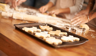 Image showing Bake, gingerbread man biscuits and people in kitchen of home, closeup for cooking or pastry preparation. Food, baking or cookies with hands of family at wooden counter in apartment for snack recipe