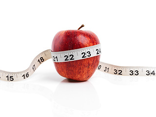Image showing Apple, wellness and tape measure with red fruit in studio isolated on white background for diet, health or nutrition. Sustainability, vitamins and size with organic produce for detox or weightloss