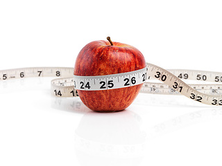 Image showing Apple, food and tape measure with red fruit in studio isolated on white background for diet, health or nutrition. Size, vitamins and minerals with organic produce for wellness, detox or weightloss