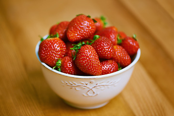 Image showing Strawberries, bowl and counter for health, wellness or organic diet on wood countertop. Fruit, nutrition or produce for eating, gourmet and meal or cuisine with vitamins or fresh for weight loss