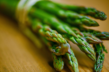 Image showing Asparagus, closeup and counter for health, wellness or organic diet on wood countertop. Vegetable, nutrition or produce for eating, gourmet and meal or cuisine with vitamins or fibre for weight loss