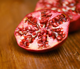 Image showing Wellness, fruit and pomegranate on wooden table in kitchen for diet, health or nutrition closeup. Food, minerals and vitamins with healthy produce on counter or surface in apartment for detox