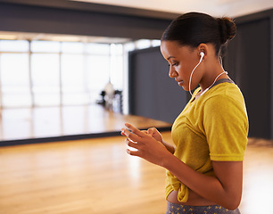 Image showing Relax, girl and listening to music with earphones connect on digital device in dance studio or gym in weekend. Audio, female person and woman streaming songs on app with technology and sound
