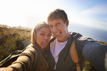 Image showing Funny, face and hiking couple with selfie in nature for bonding, fun or goofy memory at sunset. Happy, love and people embrace for silly profile picture, photography or social media travel blog photo