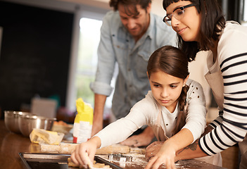 Image showing Mother, father and girl with baking cookies in kitchen with pan, happiness and teaching with support. Family, parents and child with helping, learning and bonding with cooking for dinner and snack