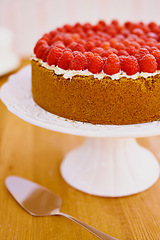 Image showing Plate, spoon and cheesecake with cream and raspberries on table for sweet snack for tea time at home. Bakery, catering and gourmet dessert with crust, frosting and fresh organic fruit in dining room.