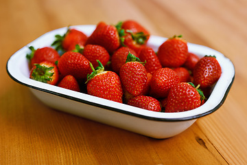 Image showing Fruit, health and strawberry bowl in kitchen of home, on wooden counter top for diet or nutrition. Food, wellness and lose weight with berries on surface in apartment for detox, minerals or vitamins