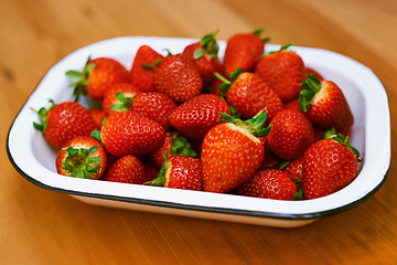 Image showing Fruit, food and strawberry bowl in kitchen of home, on wooden counter top for diet or nutrition. Health, wellness and lose weight with berries on surface in apartment for detox, minerals or vitamins