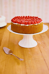 Image showing Stand, spoon and cheesecake with cream and raspberries on table for sweet snack for tea time at home. Bakery, catering and gourmet dessert with crust, frosting and fresh organic fruit in dining room.