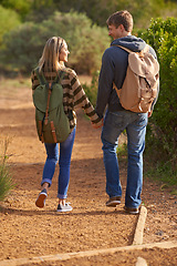 Image showing Path, hiking and happy couple holding hands in nature for holiday, travel or adventure outdoor with backpack. Rear view, man or woman trekking in the countryside on vacation, journey or date together