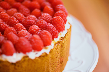 Image showing Plate, frosting and cheesecake with raspberries on table for sweet snack for tea time at home. Bakery, catering and closeup of gourmet dessert with crust, cream and fresh organic fruit in dining room