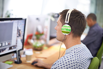 Image showing Business, designer and man with headphones at computer screen in office for creative internship and web design. Employee, rear view and monitor for multimedia production and video animation at desk