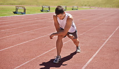 Image showing Fitness, running and stretching with athlete man getting ready on track for sports, race or competition. Exercise, training and warm up with confident young person at stadium or venue for event