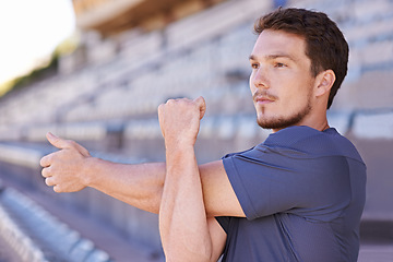 Image showing Fitness, arms and man stretching in stadium for race, marathon or competition training for health. Sports, energy and male runner athlete with warm up exercise for running cardio workout on track.