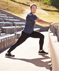 Image showing Fitness, legs and portrait of man stretching at stadium for race, marathon or competition training. Sports, health and male runner athlete with warm up exercise for running cardio workout on track.