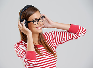 Image showing Woman, headphones and music listening in studio or streaming app as subscription, connection or entertainment. Female person, glasses and rock audio on grey background for jazz sound, track or mockup