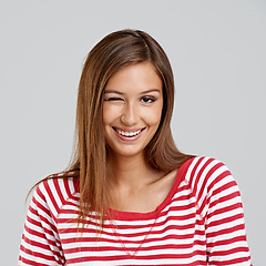 Image showing Woman, wink and smile for fashion in studio on grey background with casual, street wear and smart in confidence. Portrait, female person and happy or satisfied with trendy outfit and clothes.