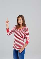 Image showing Pointing, mockup and portrait of woman for fashion, style and trendy with cool outfit isolated on gray background. Female person, hand and lady with stripe shirt, blue jeans and garments in studio