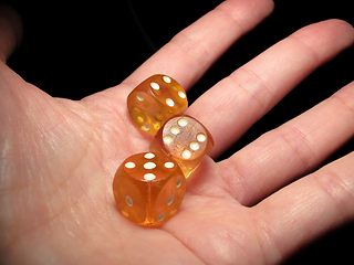 Image showing Hand holding three dice on a black background