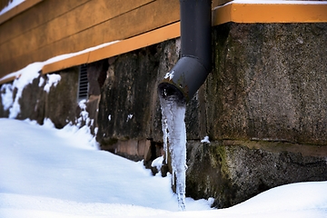 Image showing icy drainpipe near the stone foundation of an old house