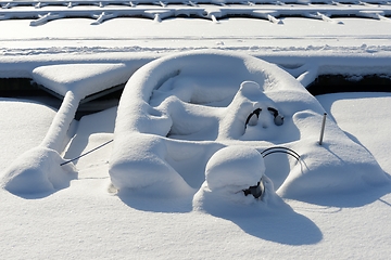 Image showing boat with motor covered with snow in winter at the boat parking