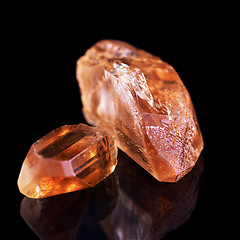 Image showing Gem, rock and orange stone in studio with isolated black background for natural resource, shine and sparkle for luxury. Crystal, jewel and reflection in closeup for citrine, glow and mineral