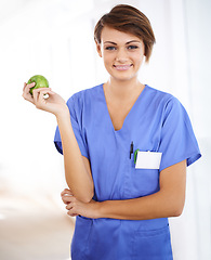 Image showing Woman, nurse and happy portrait with apple in medical office, nutrition and healthy food choice, professional nursing career. Dietician, healthcare and fruit for wellness with fibre and vitamins