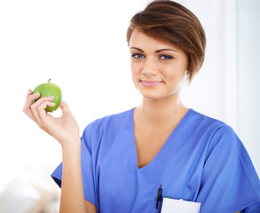 Image showing Woman, nurse and smile portrait with apple in medical office, nutrition and healthy food choice, professional nursing career. Dietician, healthcare and fruit for wellness with fibre and vitamins