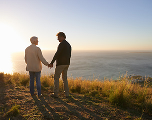 Image showing Happy, vacation and couple holding hands at sunset in nature, outdoor on hill or mountain in Cape Town. People, love and support with kindness on holiday adventure in countryside and relax together