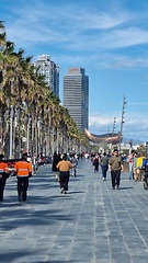 Image showing BARCELONA, SPAIN - APRILL 2, 2024: Group of people walking down street next to palm trees