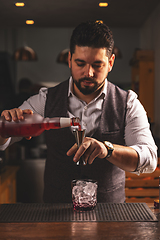 Image showing Professional bartender pouring cocktail at bar