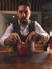 Image showing Expert bartender garnishing cocktail at bar