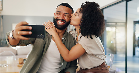 Image showing Happy couple, kiss and selfie in home with cellphone, hug and bonding on weekend together with love. Man, woman and profile picture to post on social media, romantic and funny face in living room