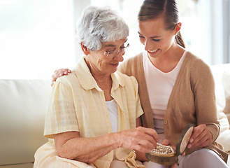 Image showing Mother, senior woman and adult daughter with pearl necklace, home and conversation in a living room. Family, pensioner and girl on a couch, relaxing and discussion with jewelry, present and gift