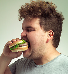 Image showing Obesity, weight gain and fast food for man in studio with hamburger for unhealthy eating,plus size and greed. Overweight person with burger in mouth and double chin for delicious, humor and comedy